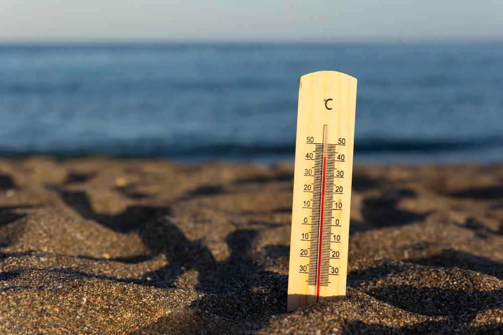 A photograph of a thermometer placed in the sand