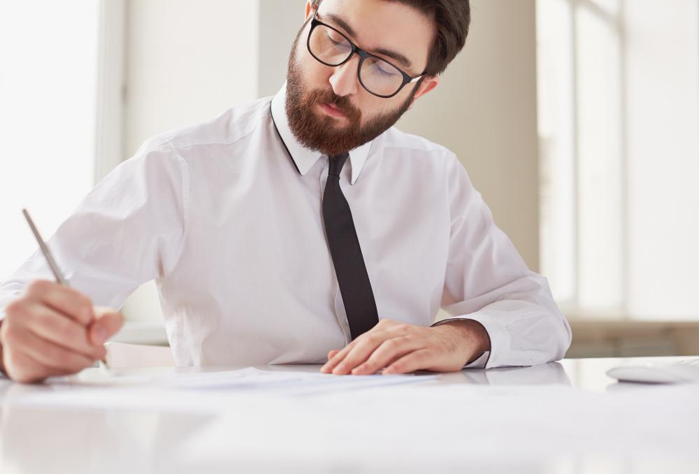 A man is pictured writing at his desk