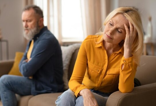 Couple looking upset, sitting on opposite sides of the couch