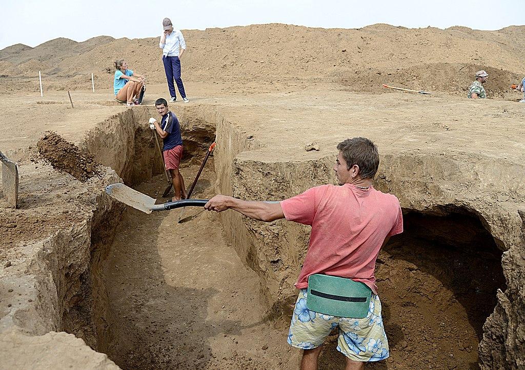 A photograph of several archaeologists digging trenches