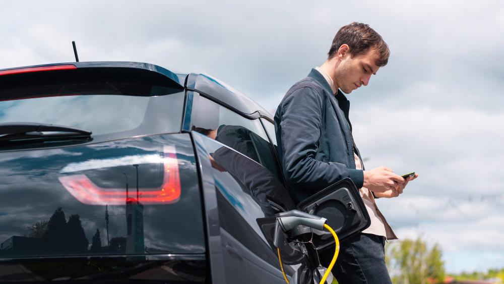 A photograph of a man pictured at a charging station