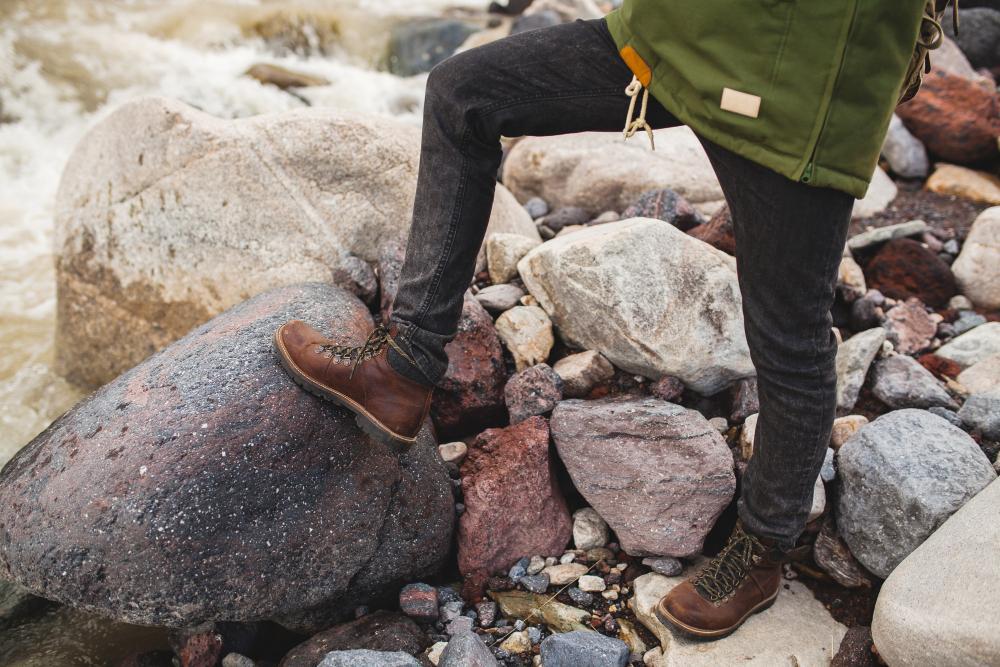 A photograph of a man standing on a large boulder