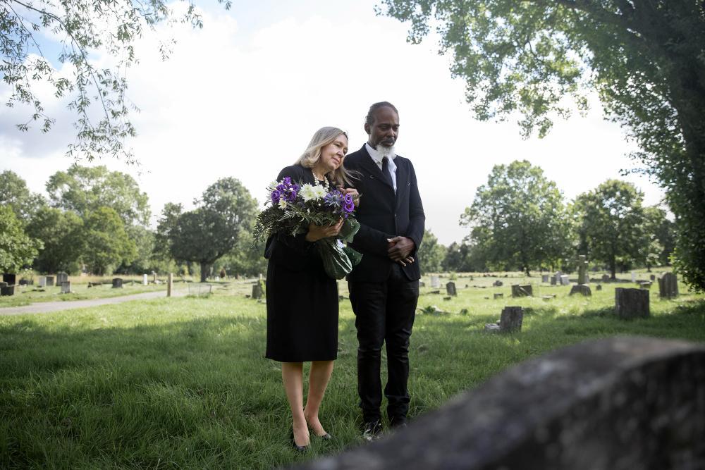 A photograph of two people standing in a graveyard