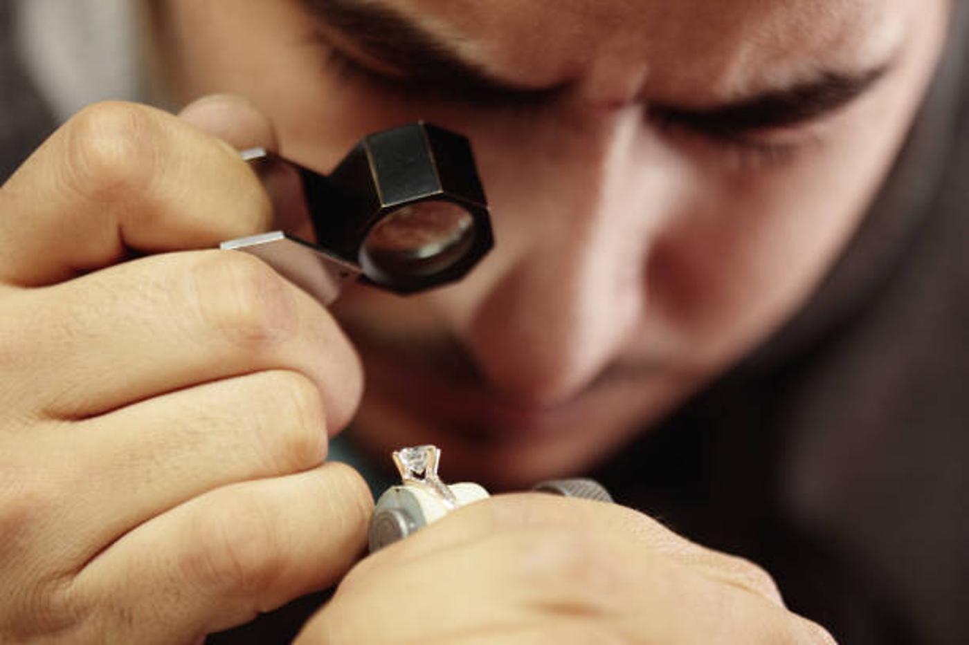 A jeweler examines a diamond with a magnifying glass