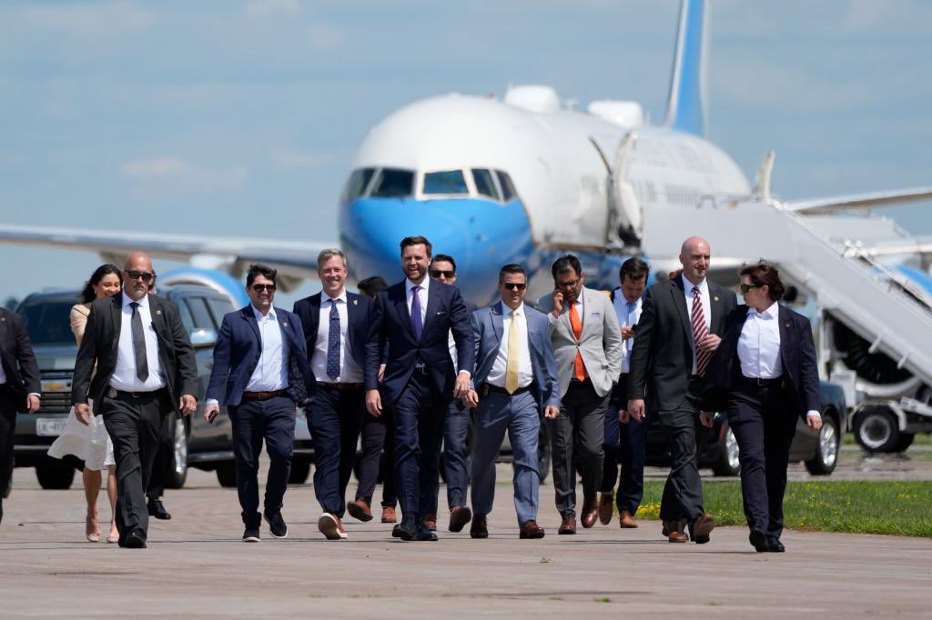 JD Vance walking away from Kamala Harris' plane with a group of people wearing suits