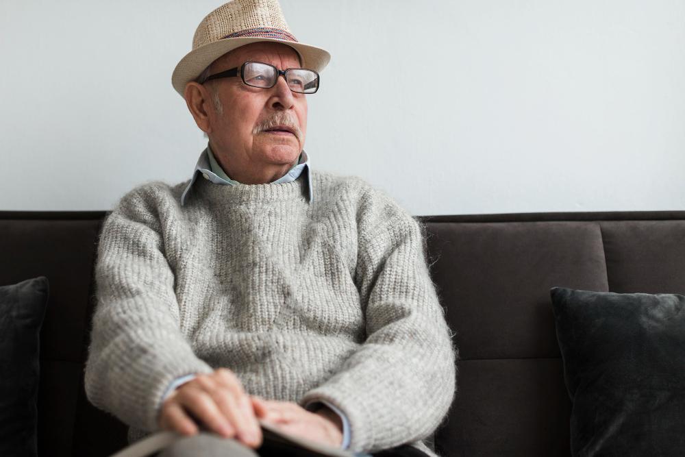 A photograph of an old man sitting on a couch