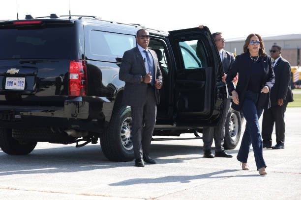 Kamala Harris leaving the door of a black SUV walking on a airport tarmac