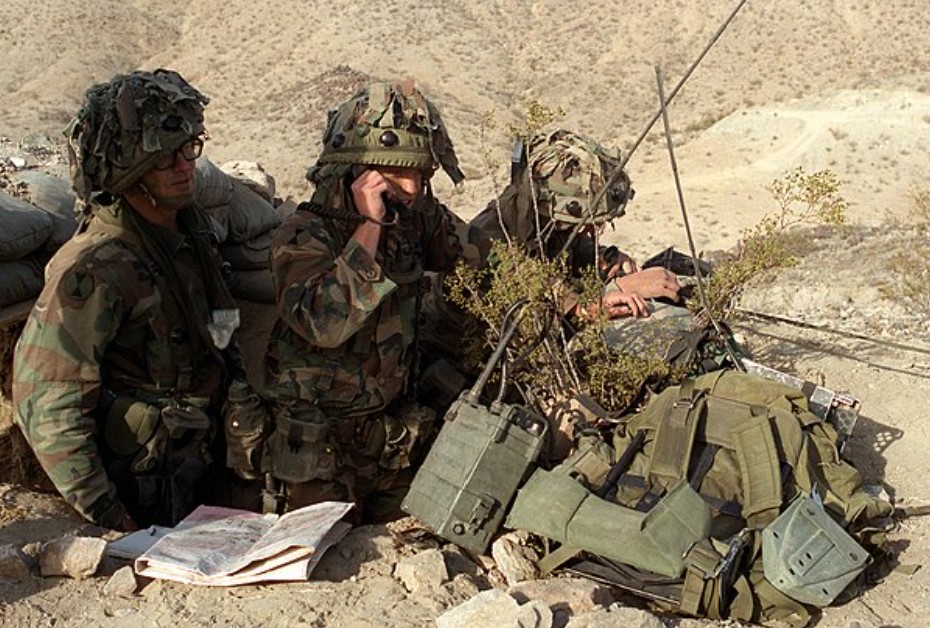 Military exercise with soldiers communicating through a radio