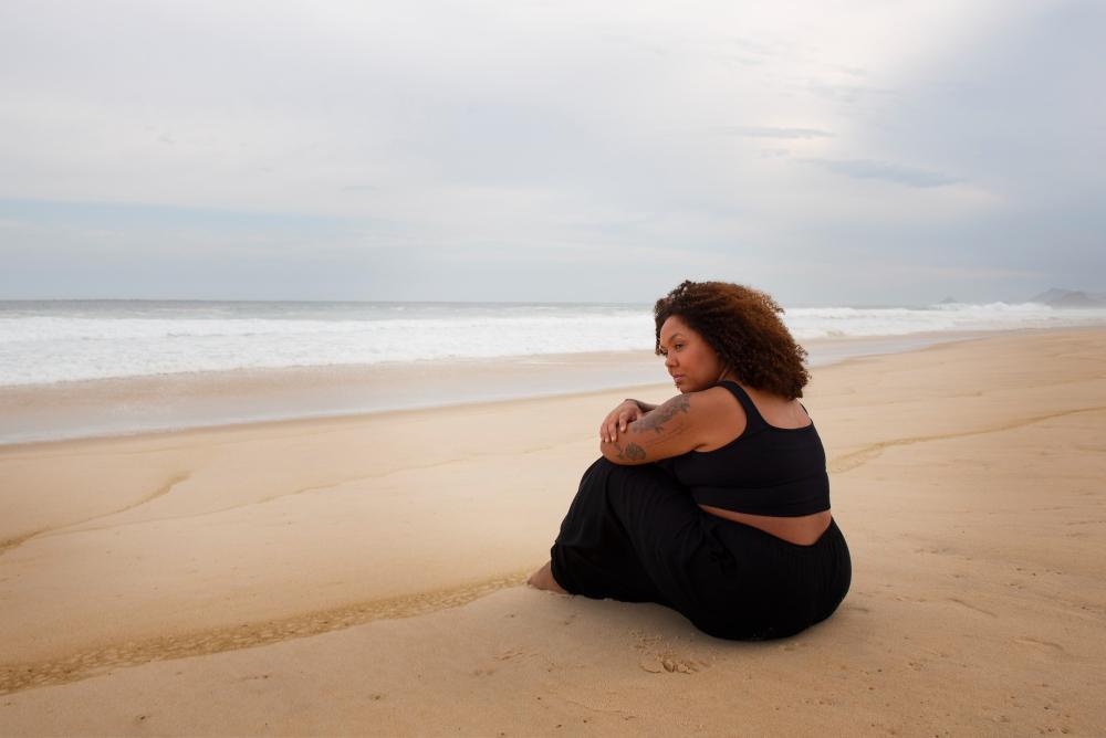 A photograph of a sad woman sitting at the beach
