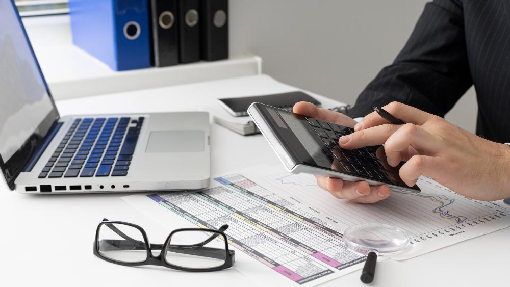 A man is pictured working on finances at his desk