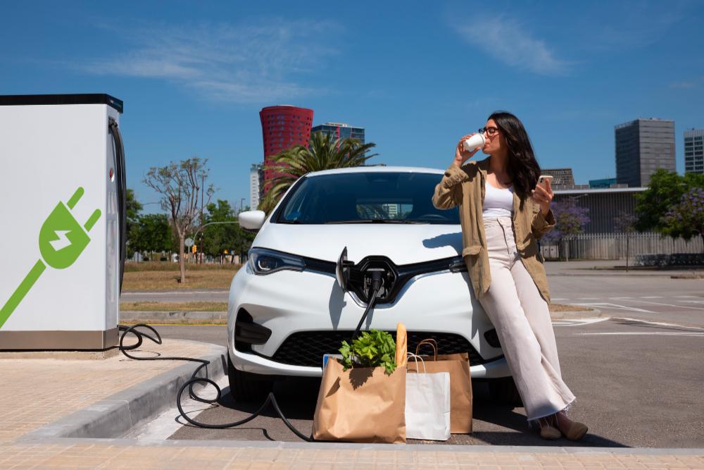 A photograph of a woman pictured charging her electric vehicle