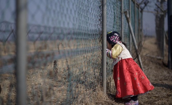 Little girl in Hanbok looking through a fence in North Korea