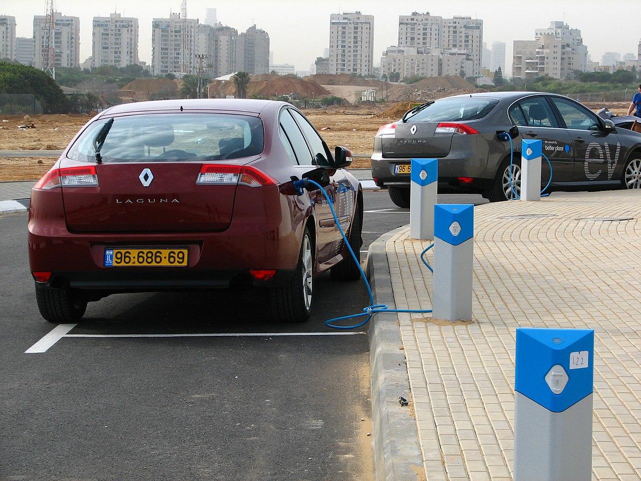 A photograph of several cars parked at a charging station