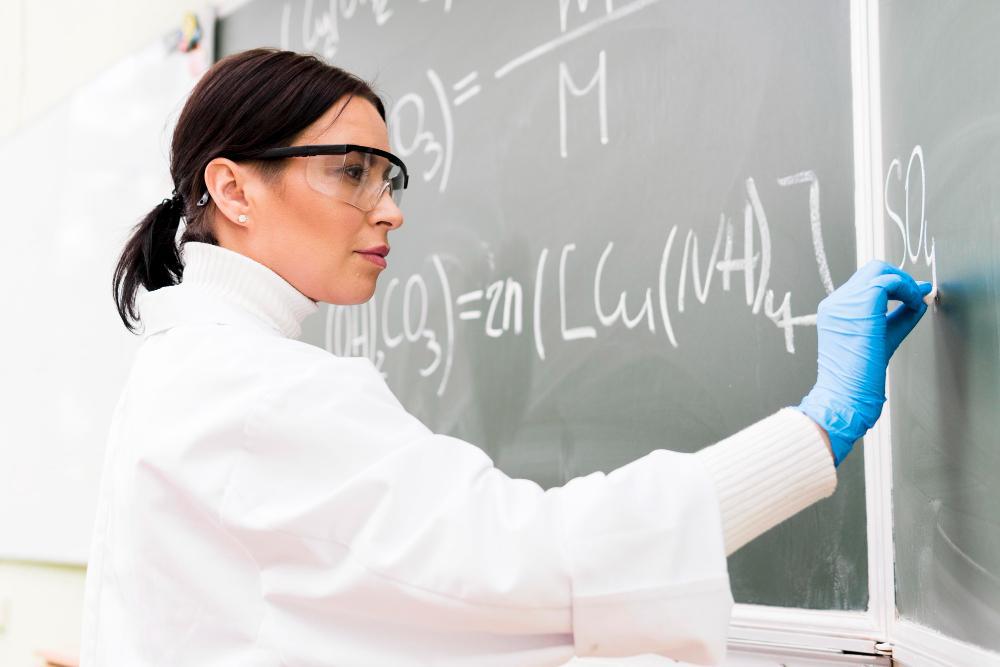 A photograph of a scientist working on several equations