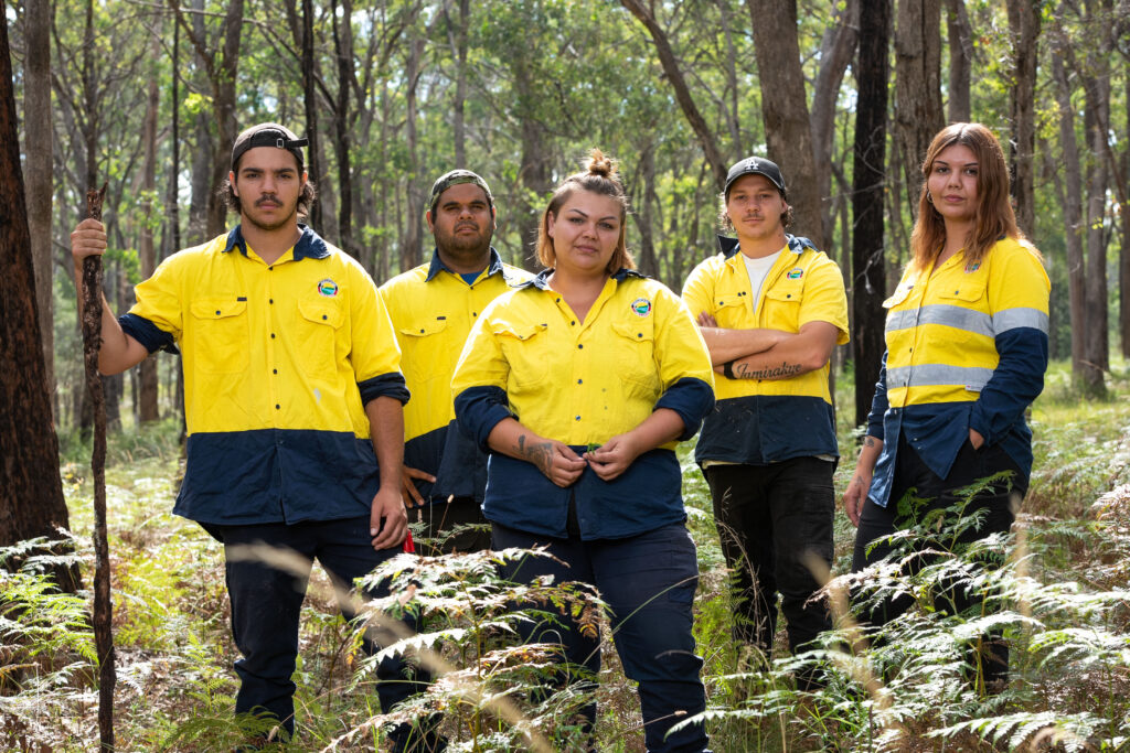 A group of Gunaikurnai people standing in the wilderness in yellow shirts