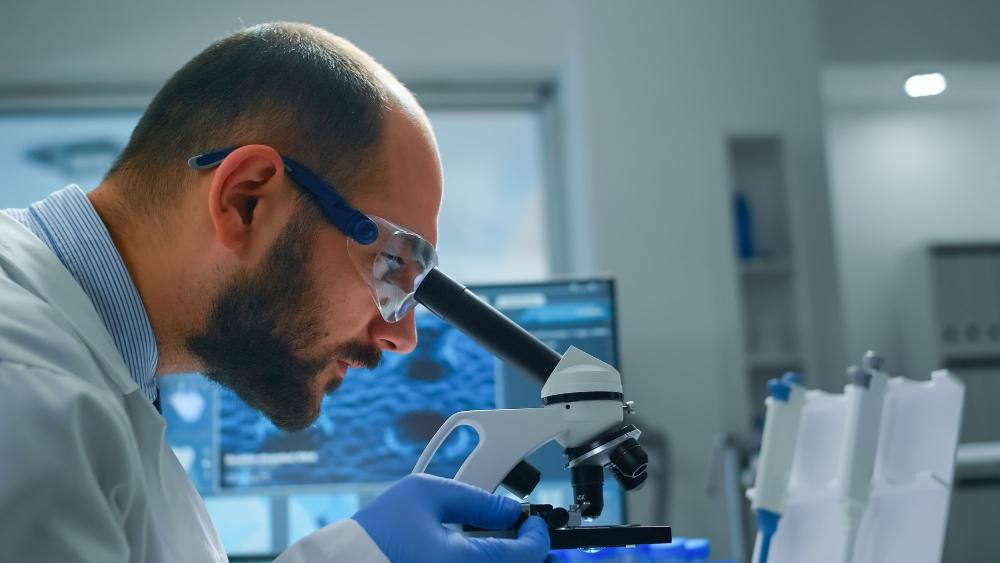 A scientist is pictured examining a test sample using a microscope