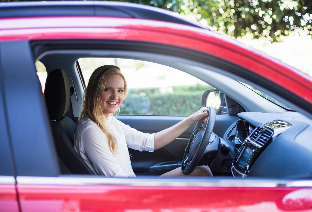A photograph of a woman driving a red car
