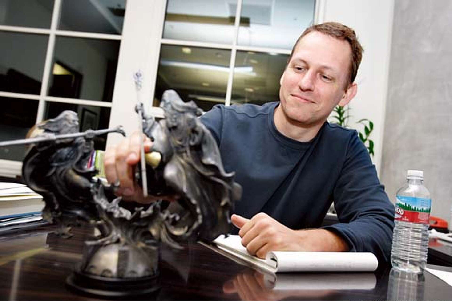 A man with red hair sitting at a desk with a set of wizard toys