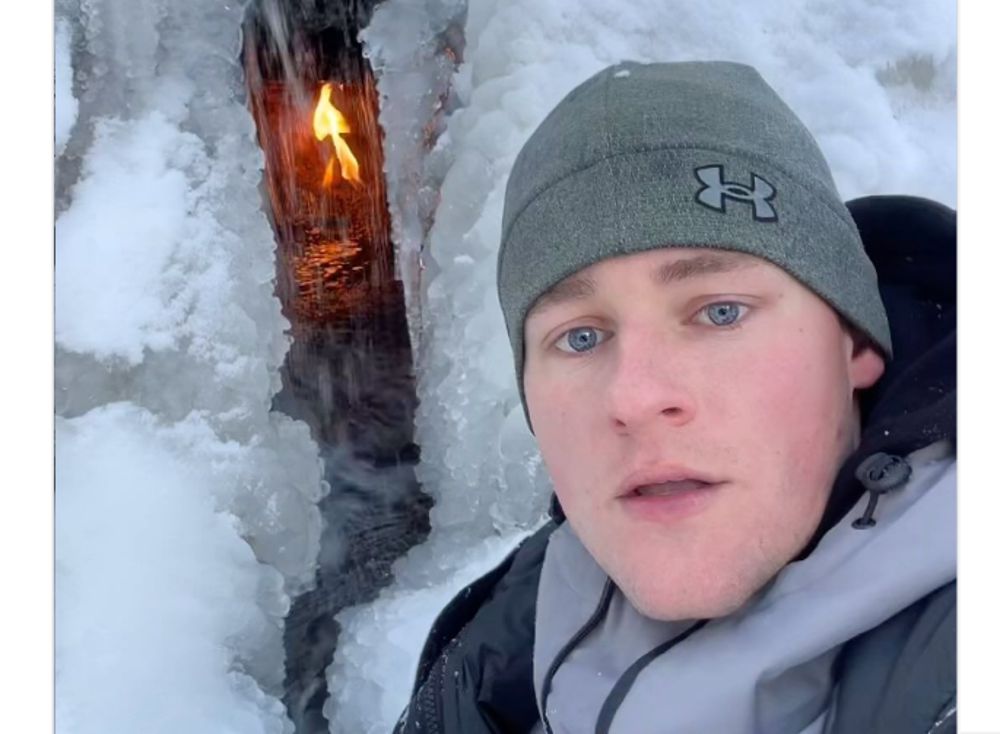 A photograph of a man standing beside an eternal flame