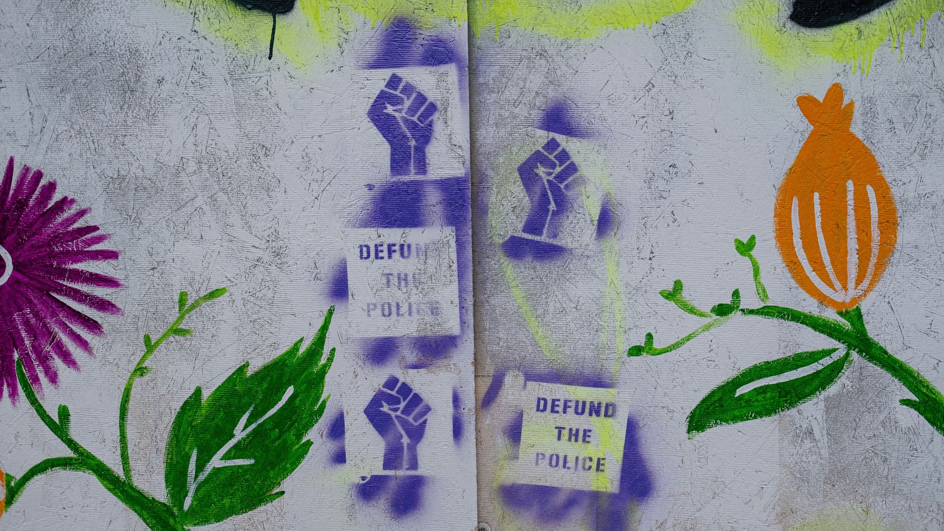 A wall with graffiti that reads to "defund the police"