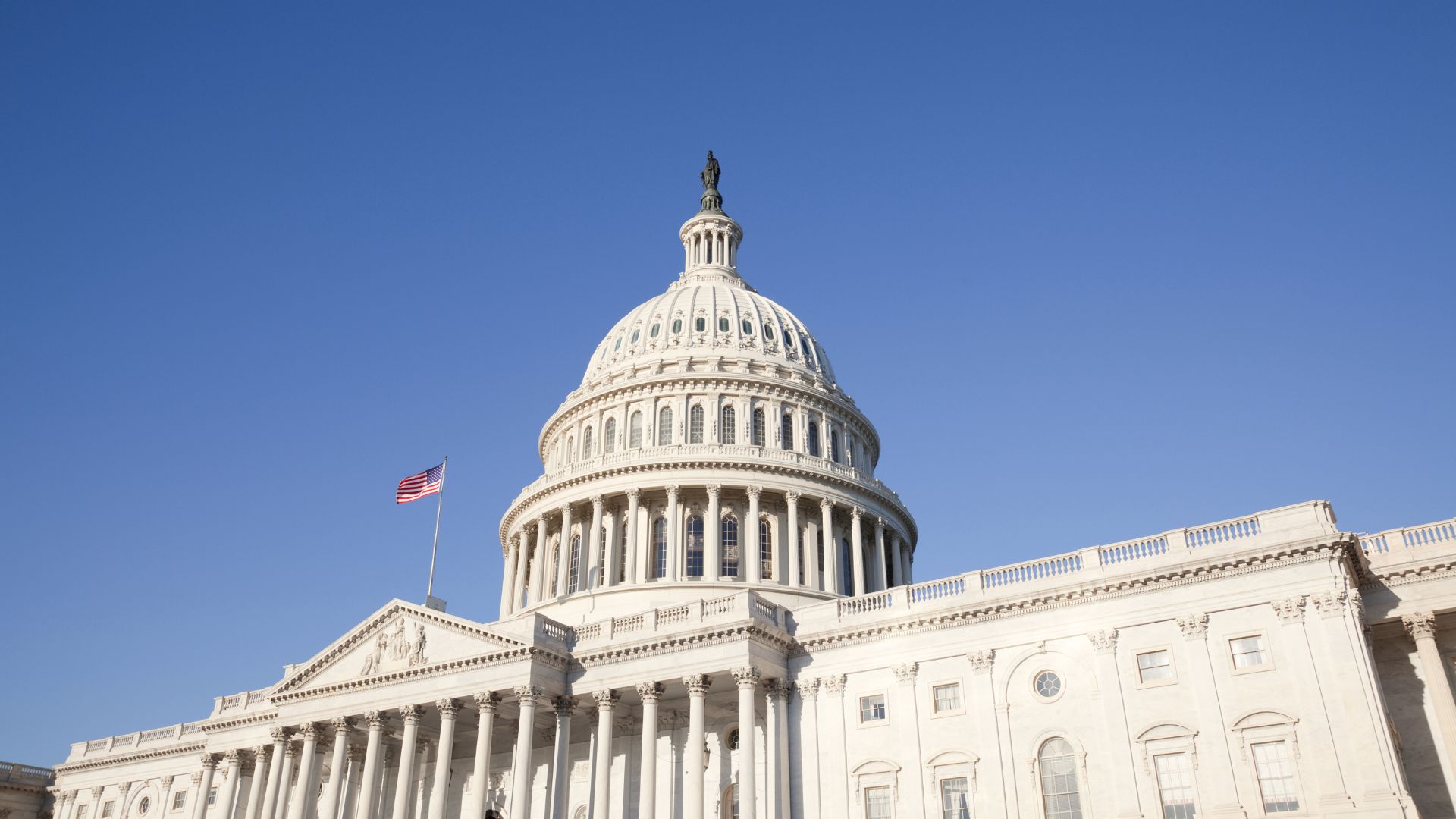The exterior of the US Congress building with a single American flag flying