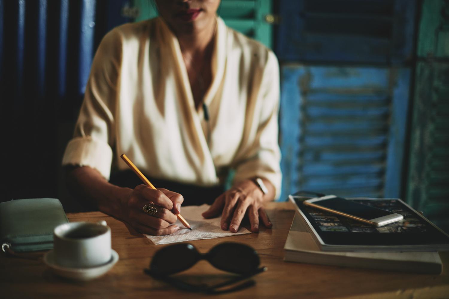 A photograph of a woman writing at her desk