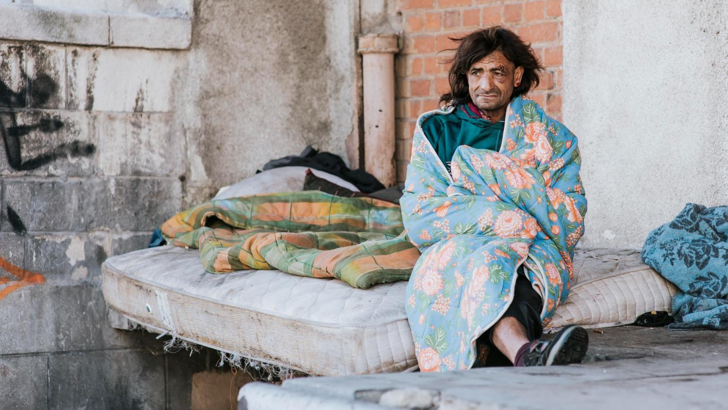 A photograph of a man sleeping on a worn out mattress