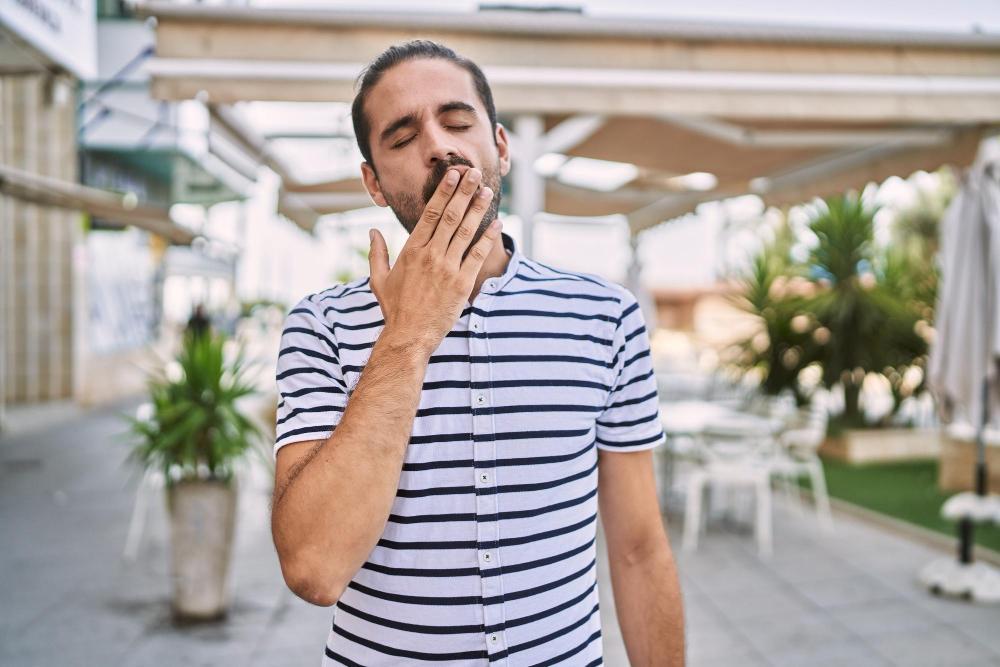 A photograph of a man yawning outside